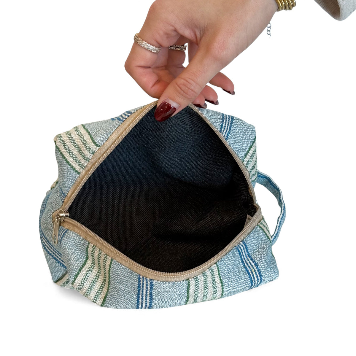 Open DE LA MUR striped makeup bag showing the dark lined interior