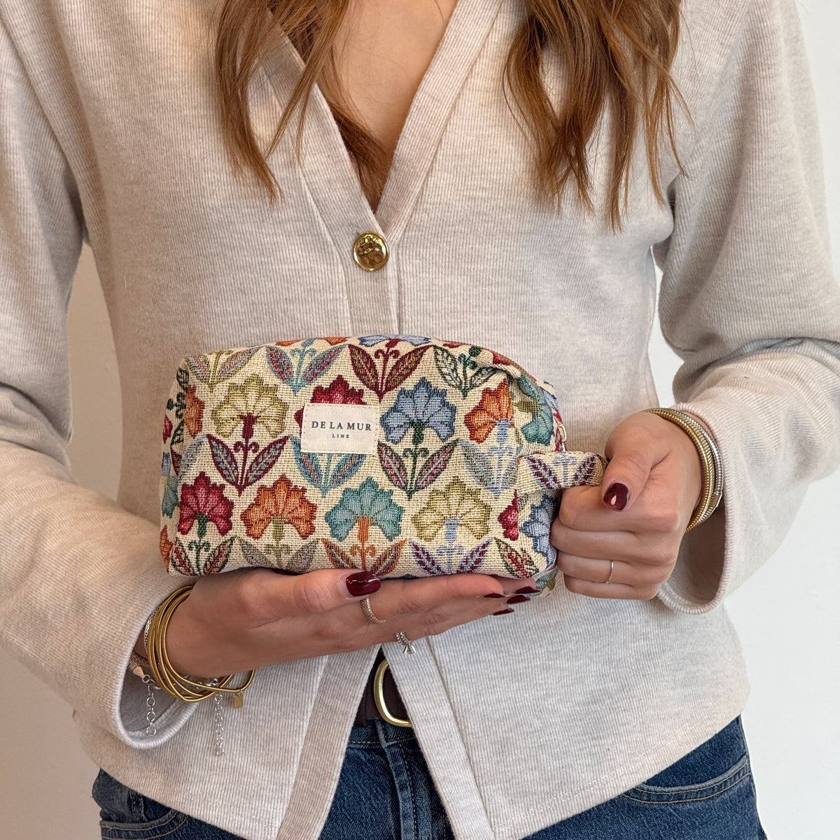 Model holding the multicolor floral DE LA MUR squared makeup bag
