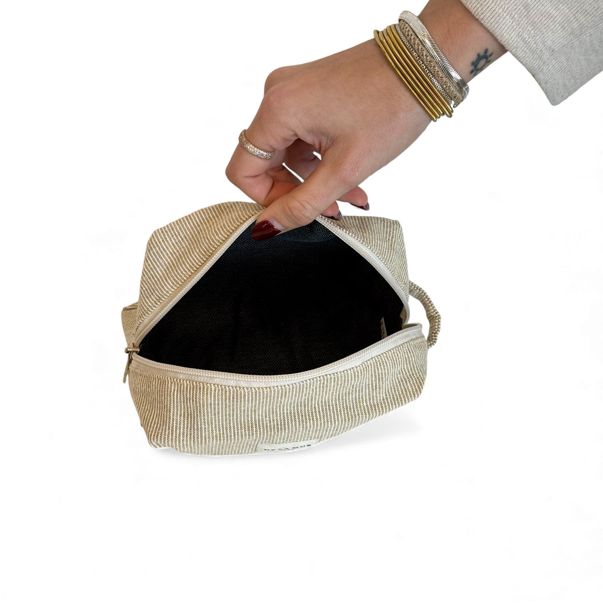 Open DE LA MUR mustard striped makeup bag showing the dark lined interior