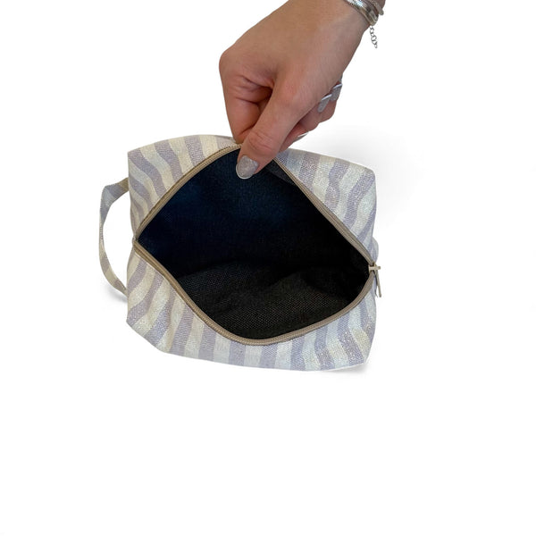 Open DE LA MUR Lulil striped makeup bag showing the dark interior