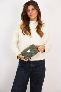 Woman holding the DE LA MUR olive green corduroy makeup bag