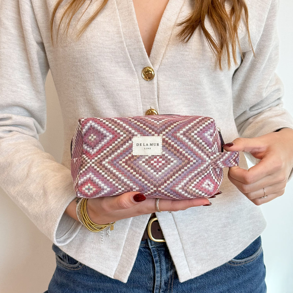 Model holding the DE LA MUR Nana geometric jacquard makeup bag