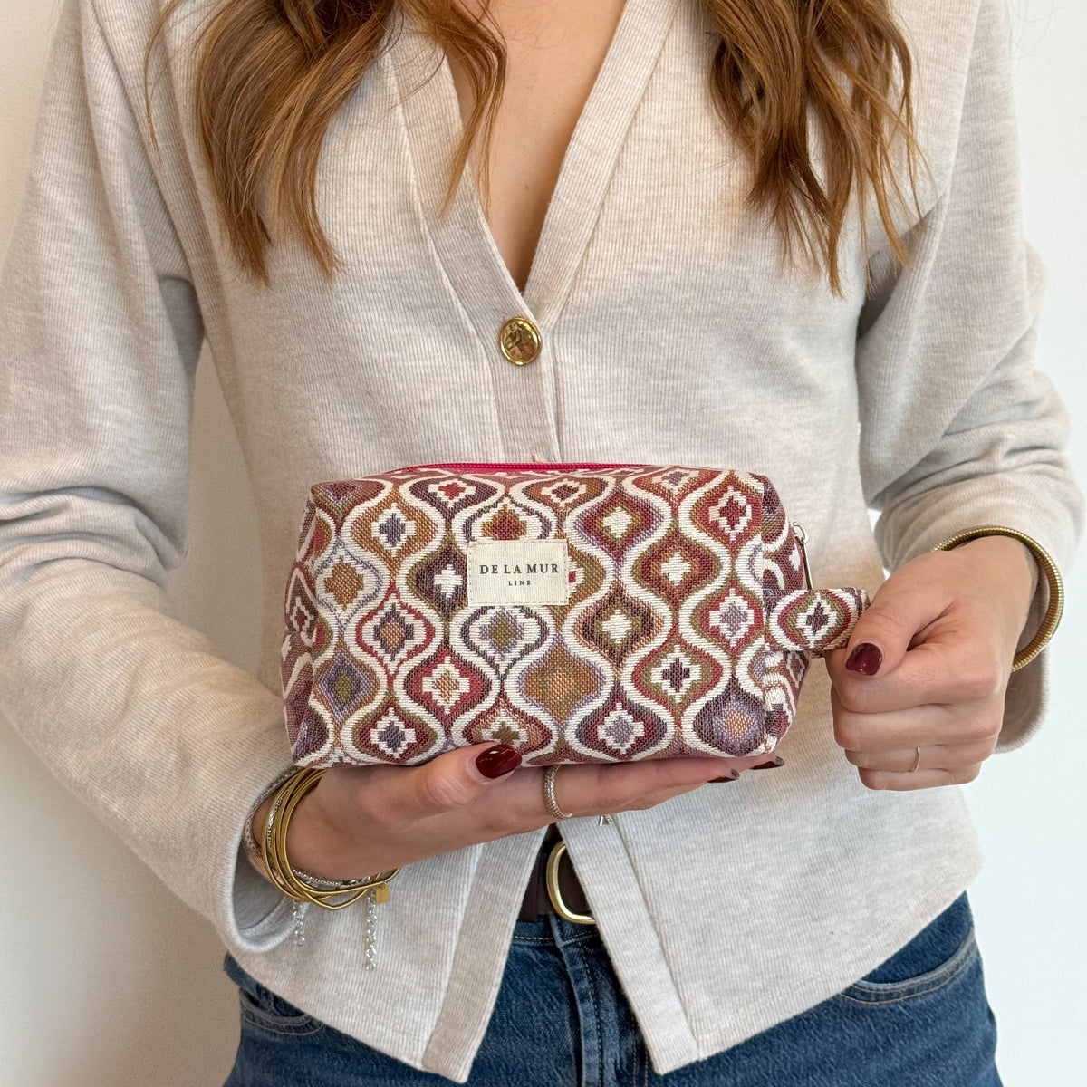 Model holding the DE LA MUR Onda jacquard makeup bag, lifestyle shot