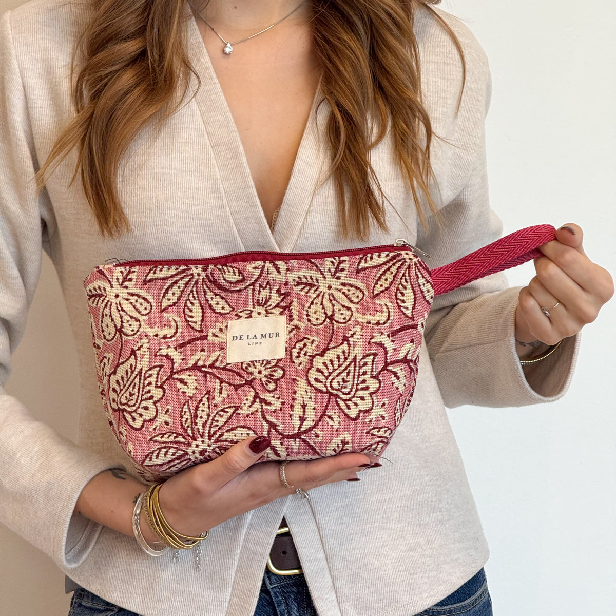 Model holding the DE LA MUR Came burgundy floral makeup bag, lifestyle shot