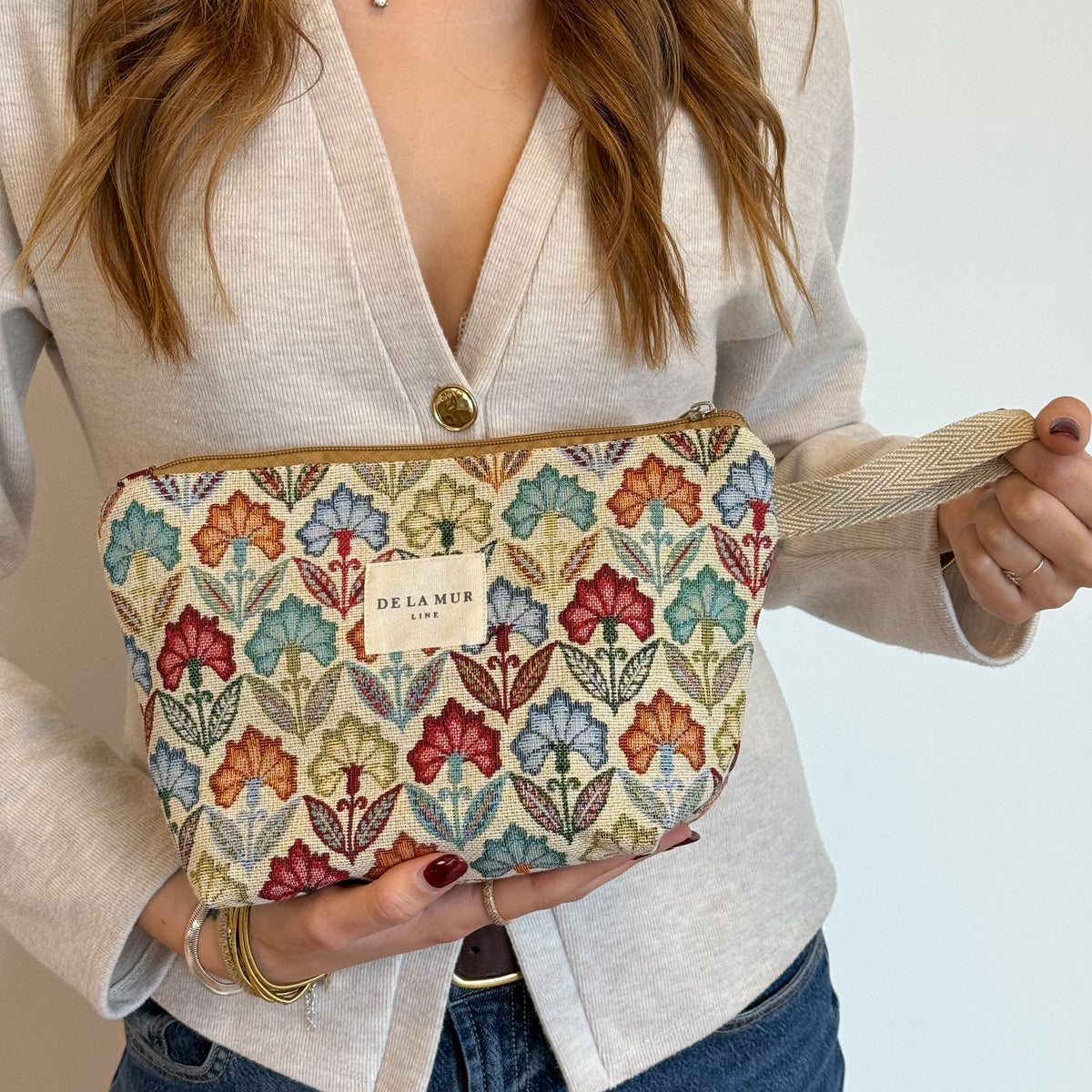Model holding the multicolor floral DE LA MUR Flora makeup bag