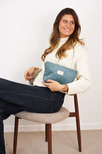 Woman holding DE LA MUR Jade teal corduroy makeup bag, lifestyle shot