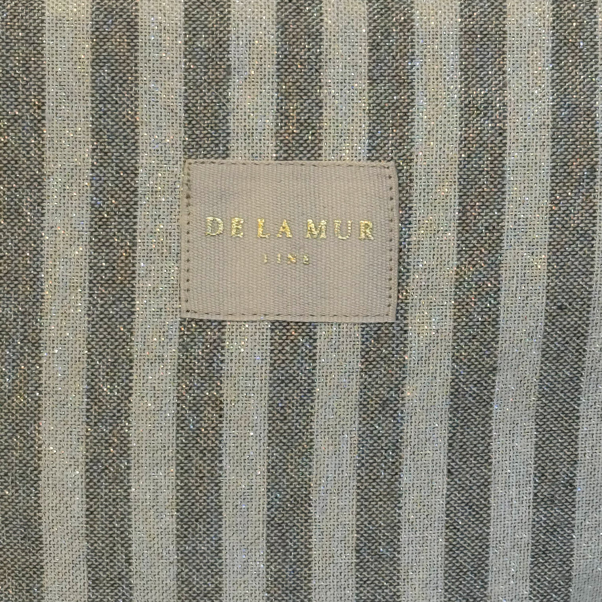 Close-up of the striped lurex fabric and DE LA MUR Line label on the Lugris bag