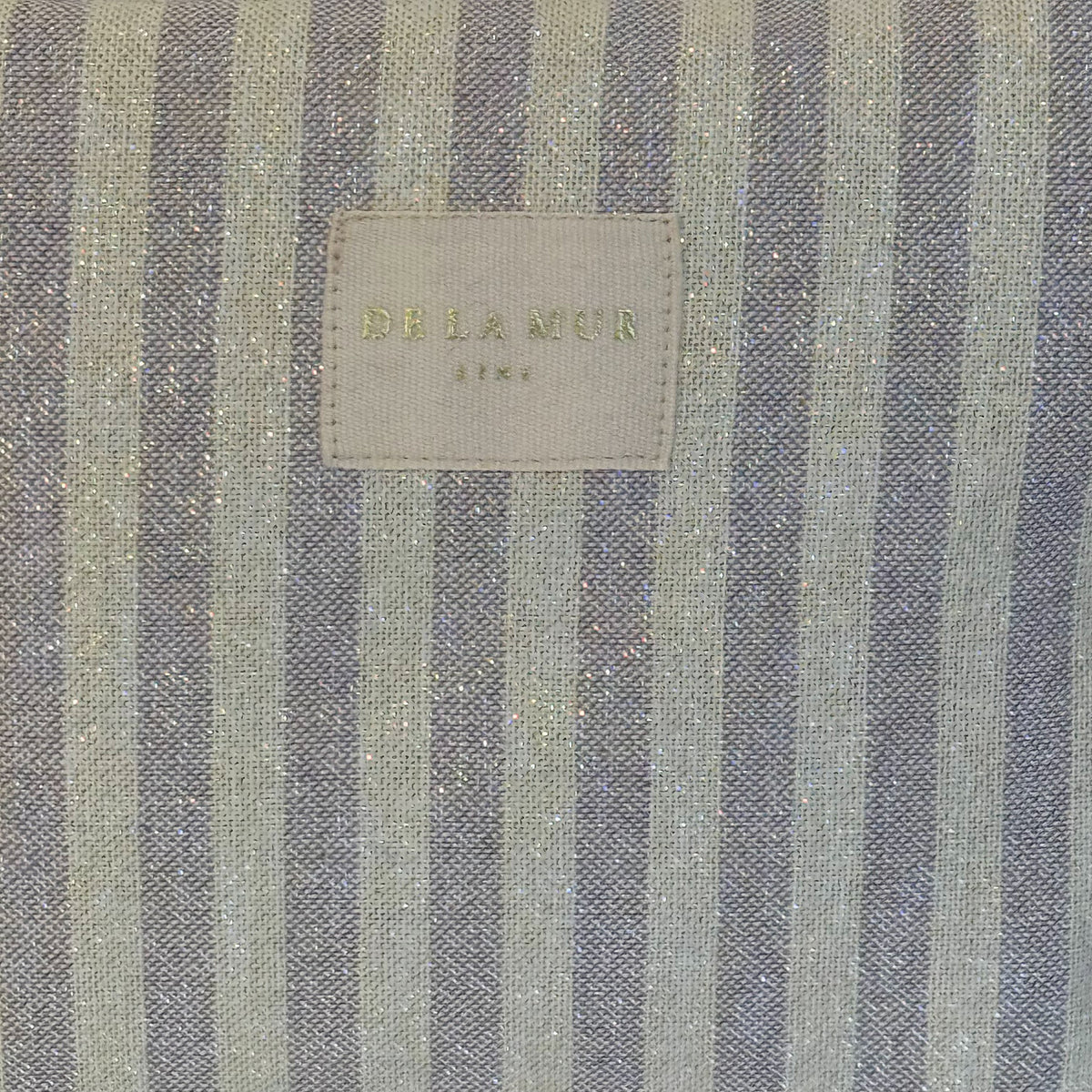 Close-up of the shimmering striped lurex fabric and DE LA MUR Line label, Lulil bag