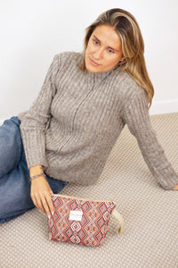 Woman on the floor beside the red multicolor DE LA MUR geometric makeup bag