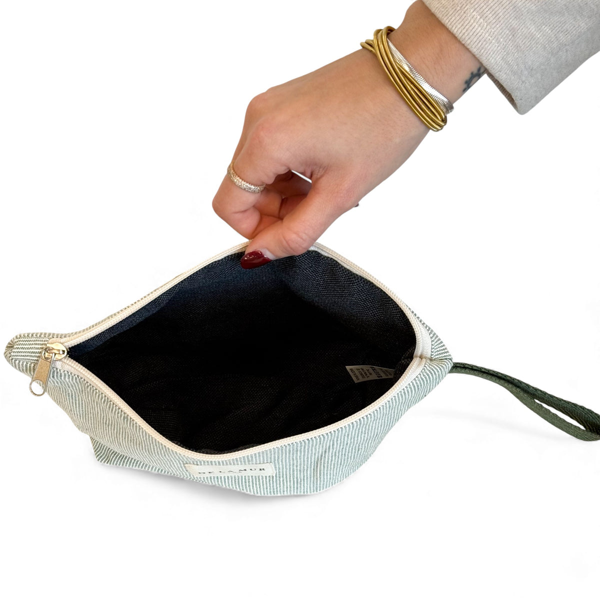 Open DE LA MUR striped makeup bag showing the dark lined interior