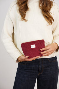 Model holding the burgundy DE LA MUR corduroy makeup bag, lifestyle shot