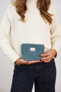 Model holding DE LA MUR teal corduroy small makeup bag (Jade)
