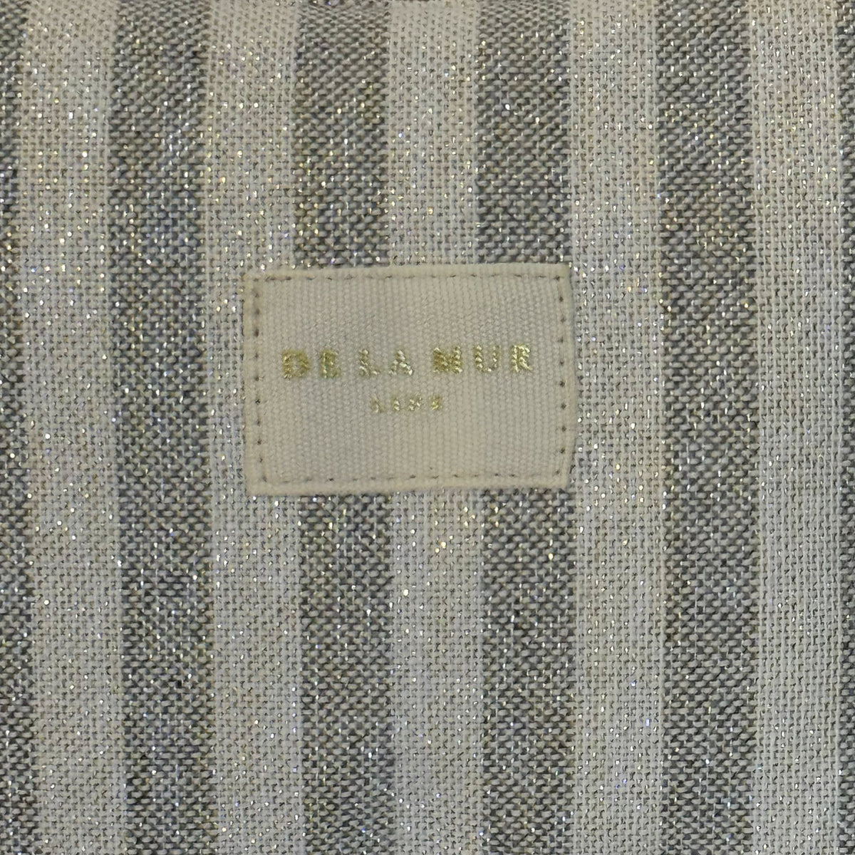 Close-up of the DE LA MUR beige and grey striped lurex fabric and Line label
