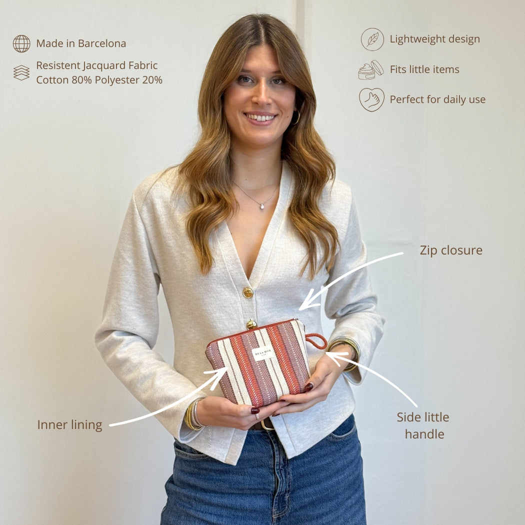 Model holding the DE LA MUR burgundy jacquard makeup bag with labeled features