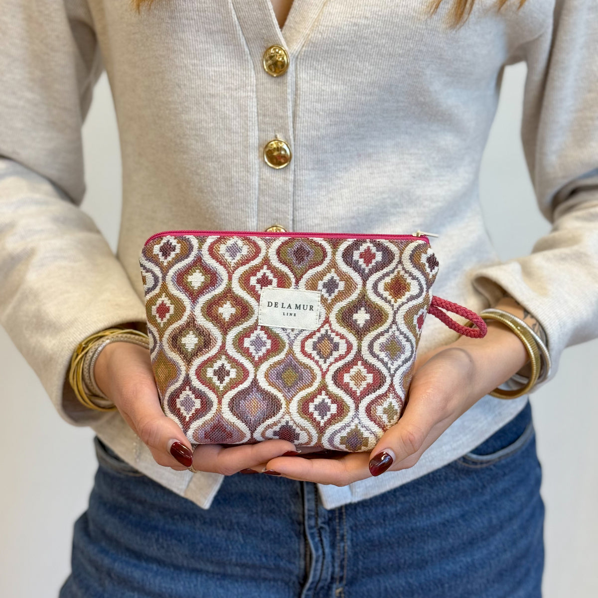Model holding the DE LA MUR Onda jacquard makeup bag in both hands