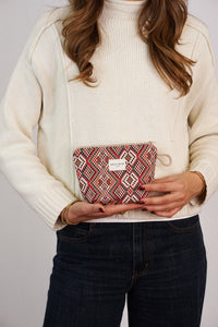 Woman holding the DE LA MUR Otto red geometric jacquard small makeup bag