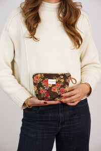 Woman holding the DE LA MUR Pepi rose floral jacquard small makeup bag