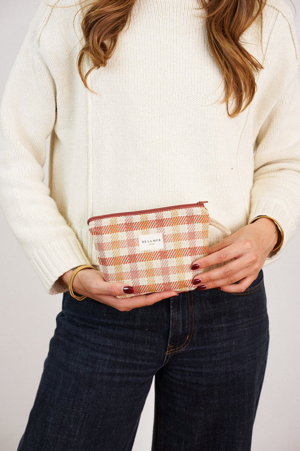 Model holding DE LA MUR terracotta gingham jacquard small makeup bag