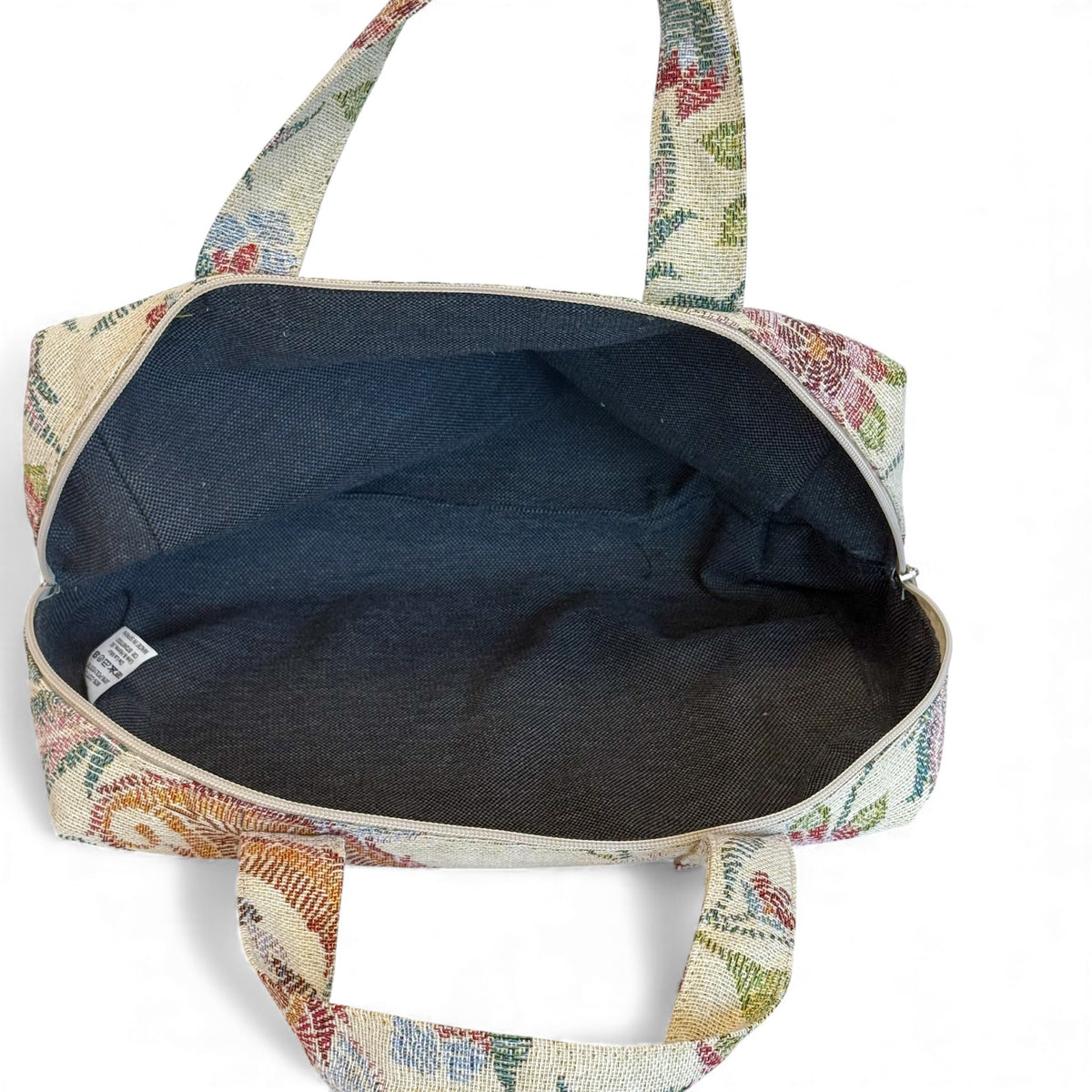 Open DE LA MUR floral makeup bag showing the dark lined interior and zip