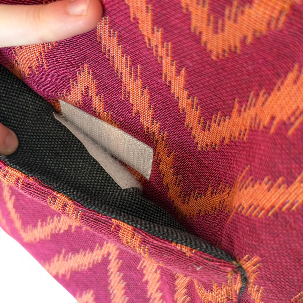 Model holding the DE LA MUR pink and orange zigzag jacquard laptop bag