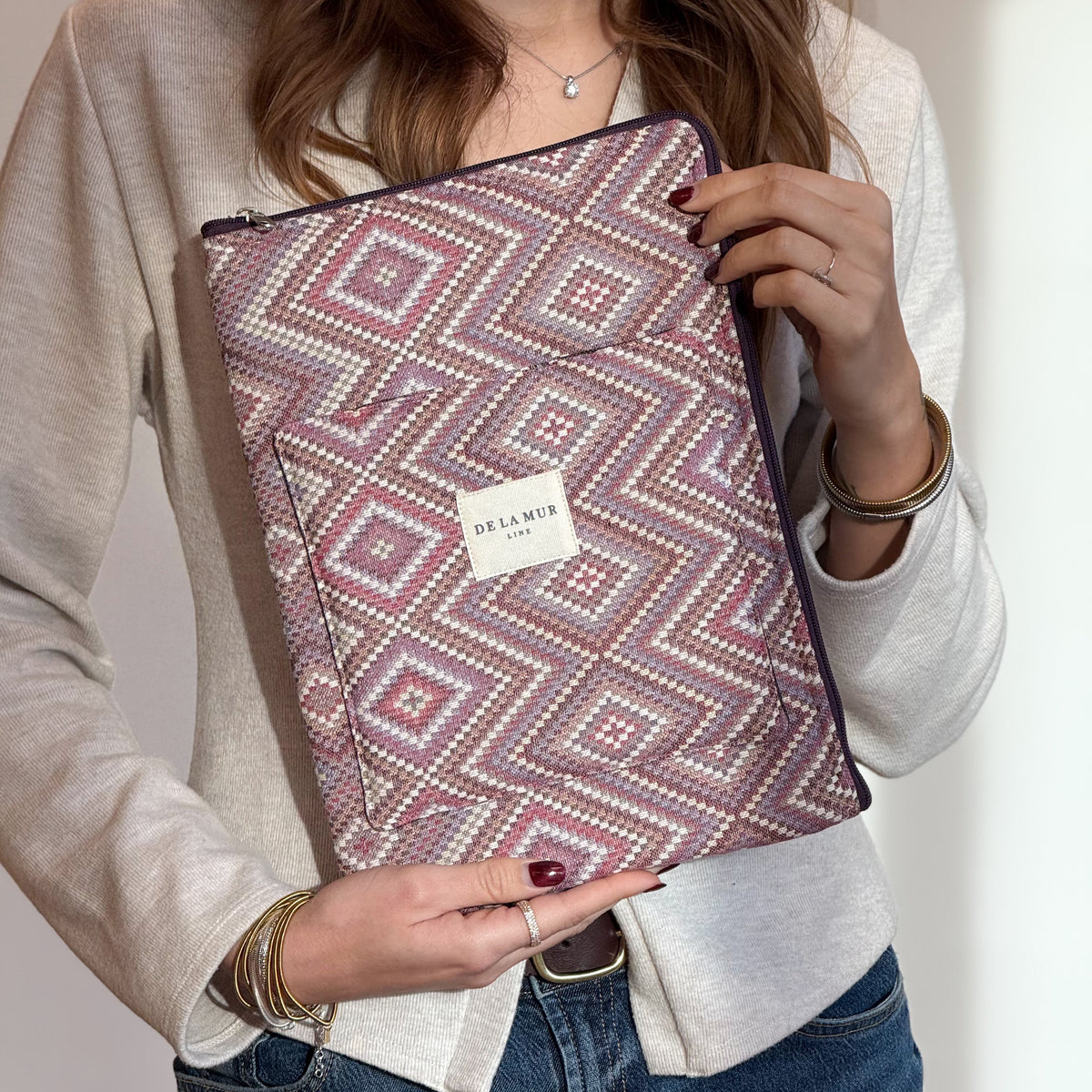 Model holding the DE LA MUR pink and lilac geometric jacquard laptop bag