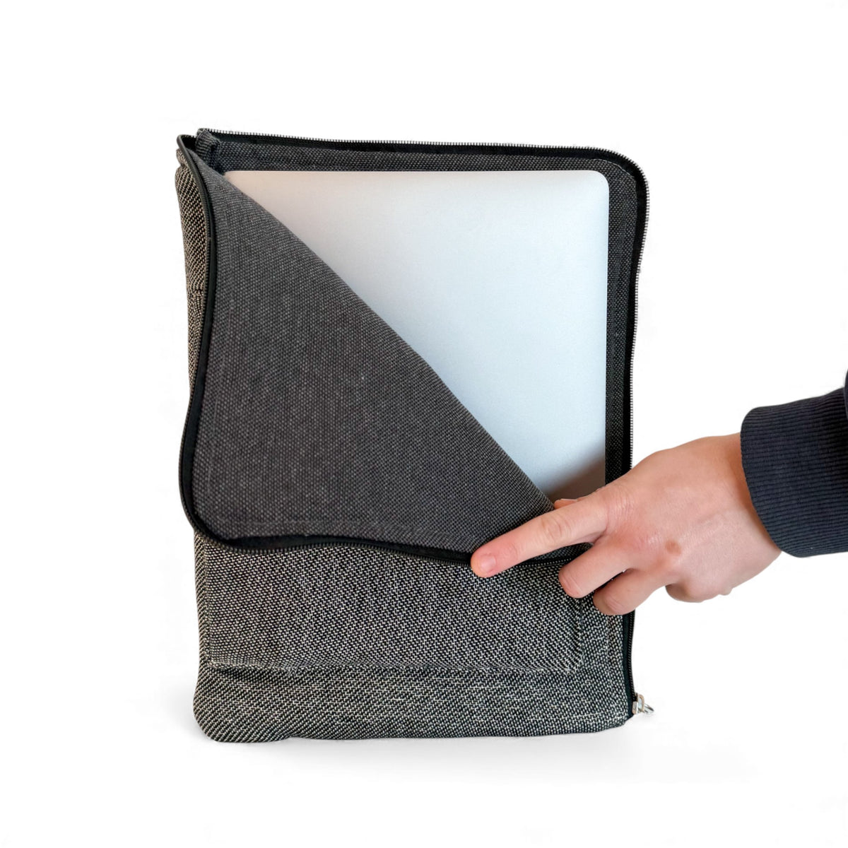 Hand sliding a laptop out of the open DE LA MUR Sinay padded laptop sleeve