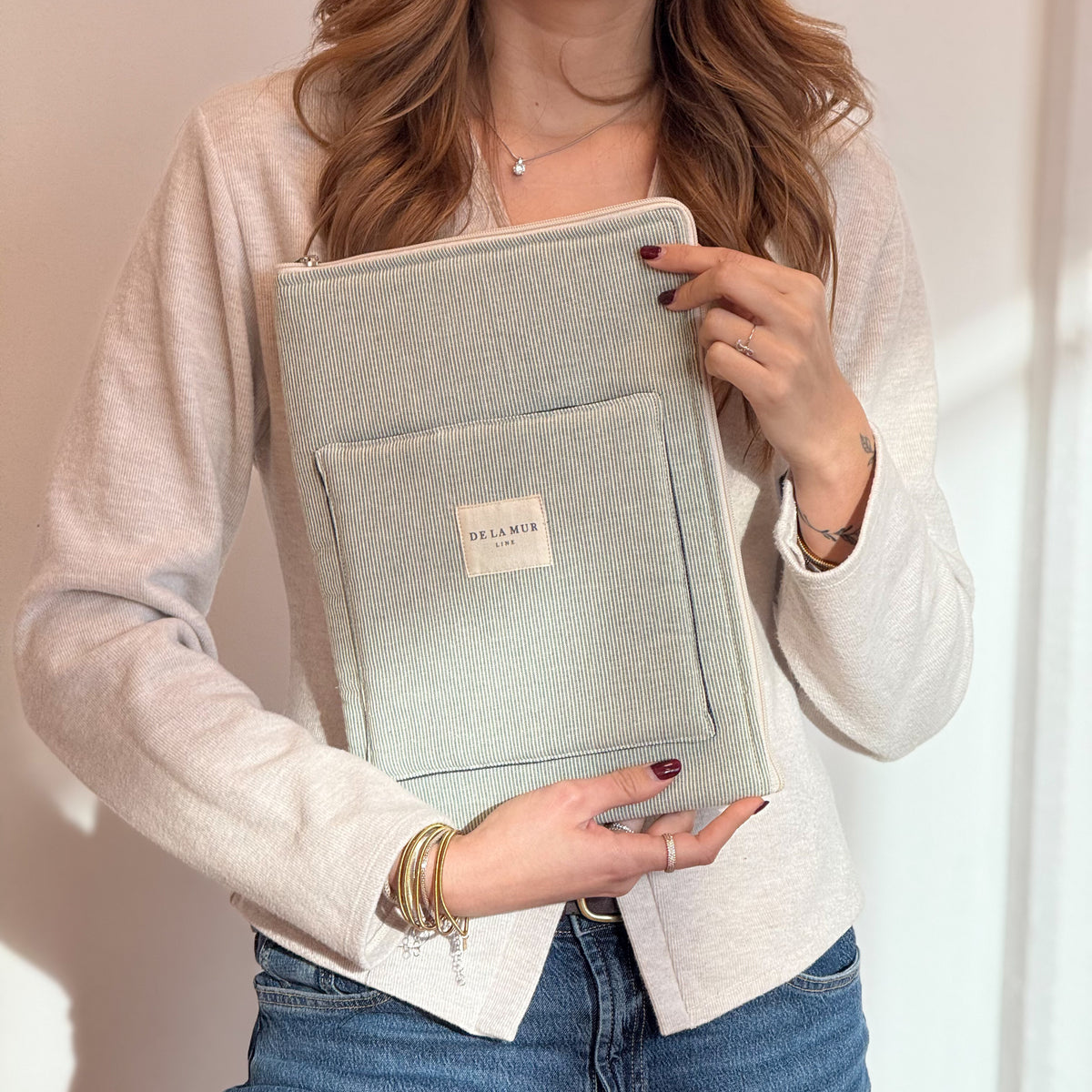 Model holding the DE LA MUR Teo green textured stripe laptop bag against her body