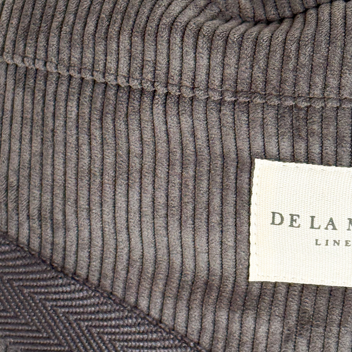 Close-up of the gray corduroy texture and DE LA MUR Line label on the Boni fanny pack