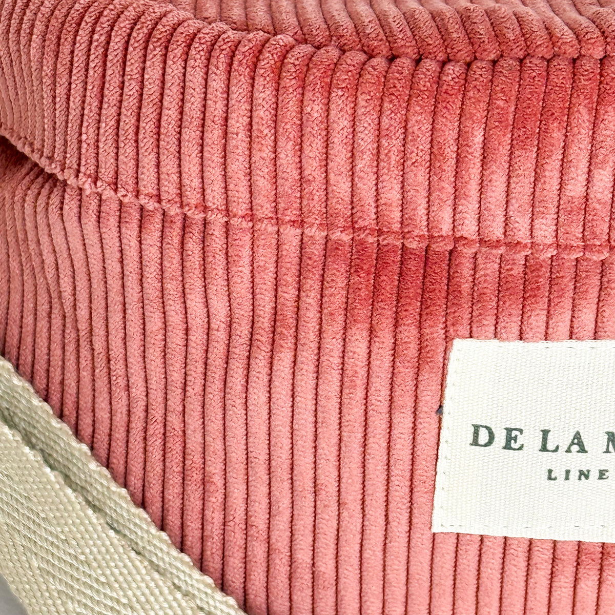 Close-up of the coral corduroy texture and DE LA MUR Line label on the Coral fanny pack