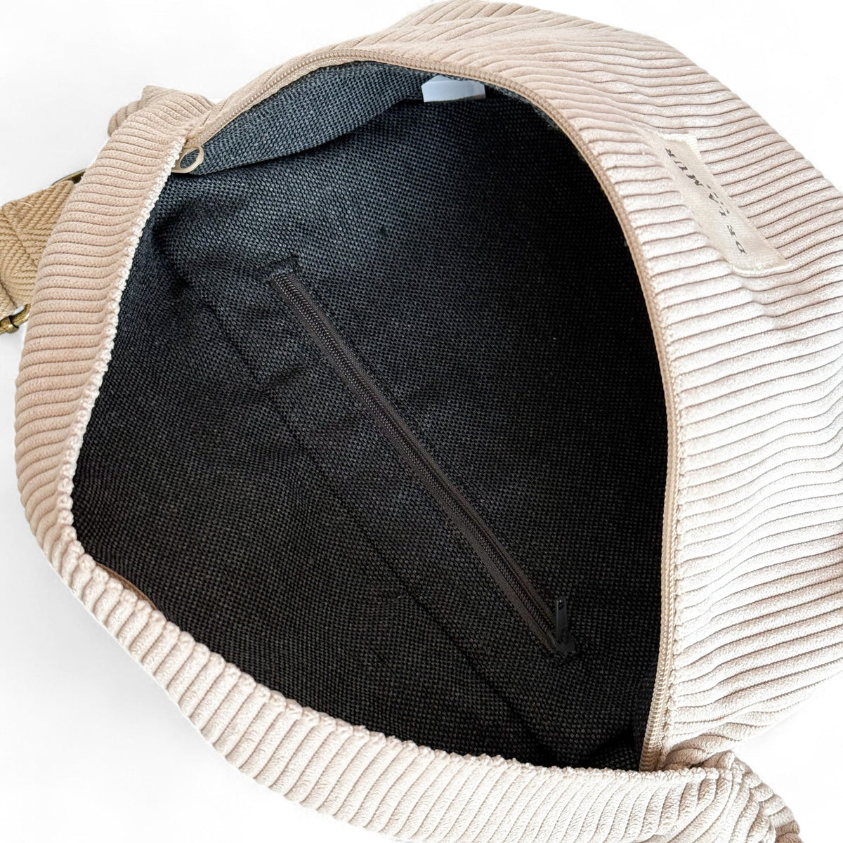 Open DE LA MUR Tofe corduroy fanny pack showing zipped inner pocket and lining