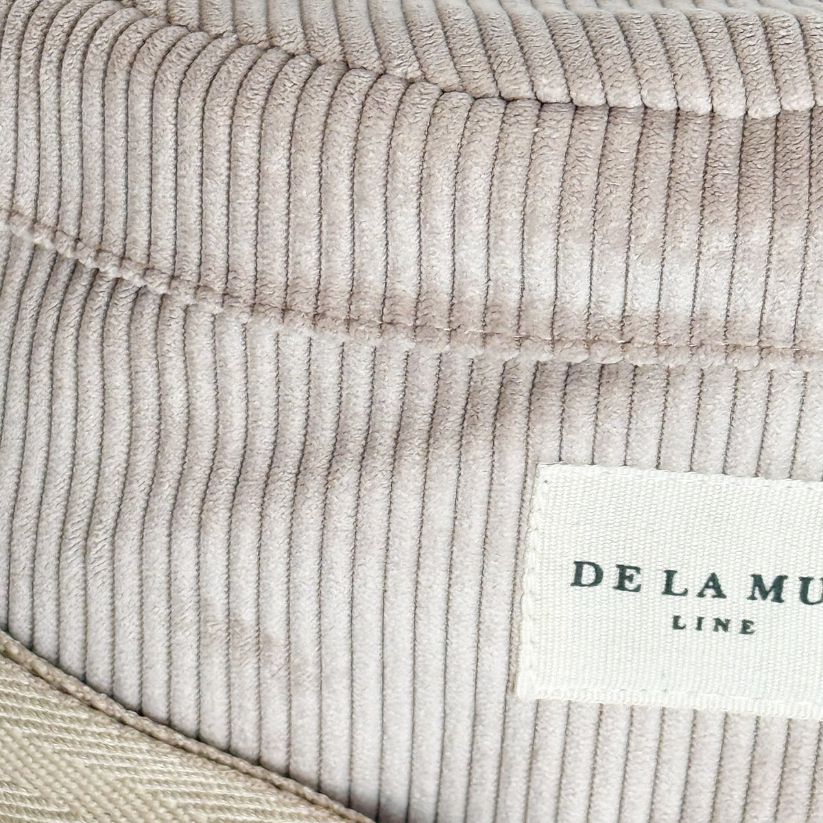 Close-up of the beige corduroy ribbing and DE LA MUR Line label on the Tofe fanny pack