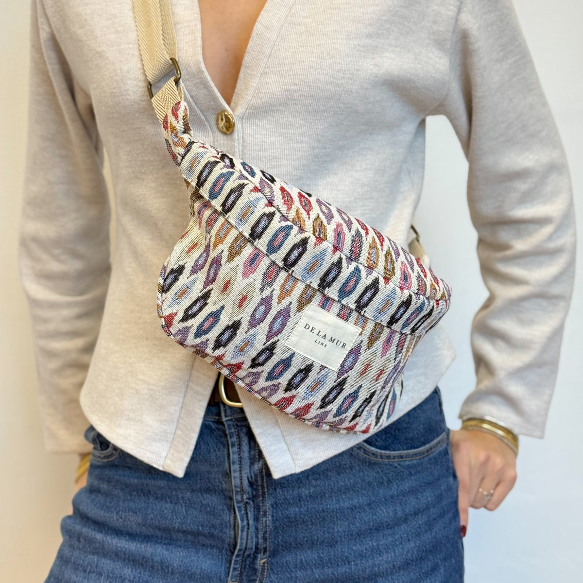 Close-up of DE LA MUR geometric Urban fanny pack worn crossbody over a cardigan
