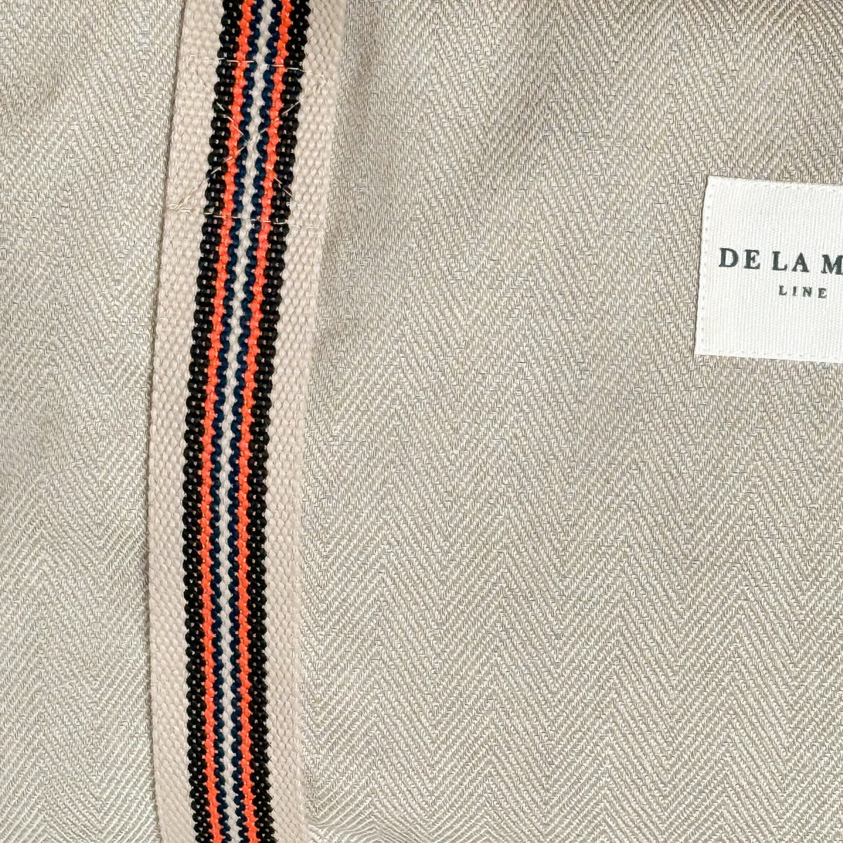 Close-up of the herringbone fabric, striped strap and DE LA MUR Line label
