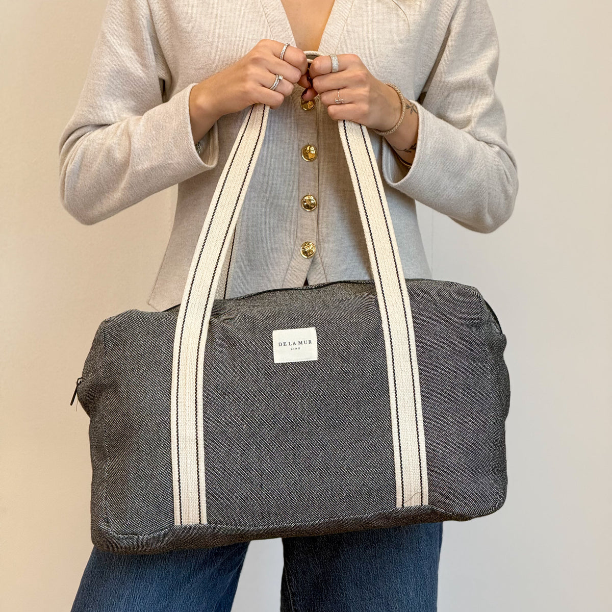 Model holding the DE LA MUR Sinay dark gray striped jacquard sports bag