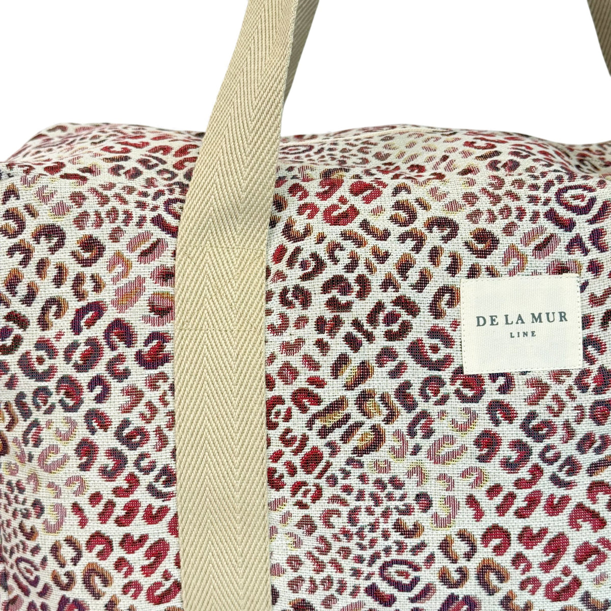 Close-up of DE LA MUR leopard jacquard fabric and Line label on the sports bag