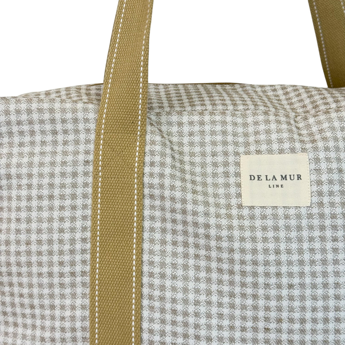 Close-up of DE LA MUR beige gingham jacquard fabric and Line label