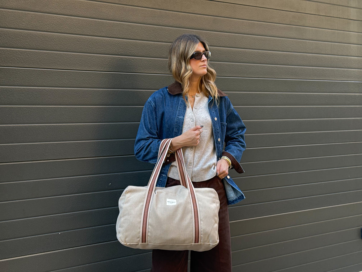 Model carrying the DE LA MUR Ivet herringbone sports bag outdoors