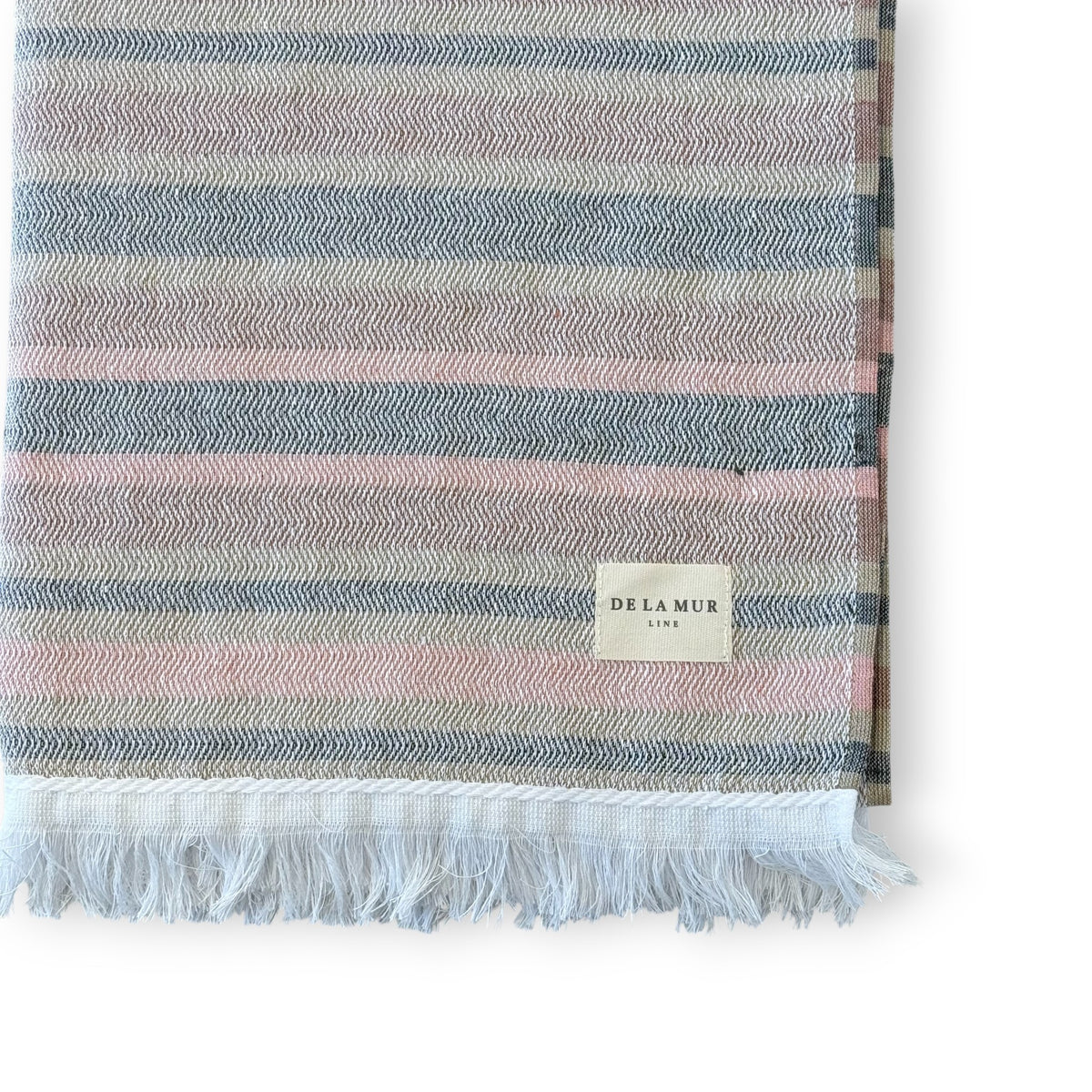 Close-up of DE LA MUR pink and grey striped towel corner, fringe and Line label