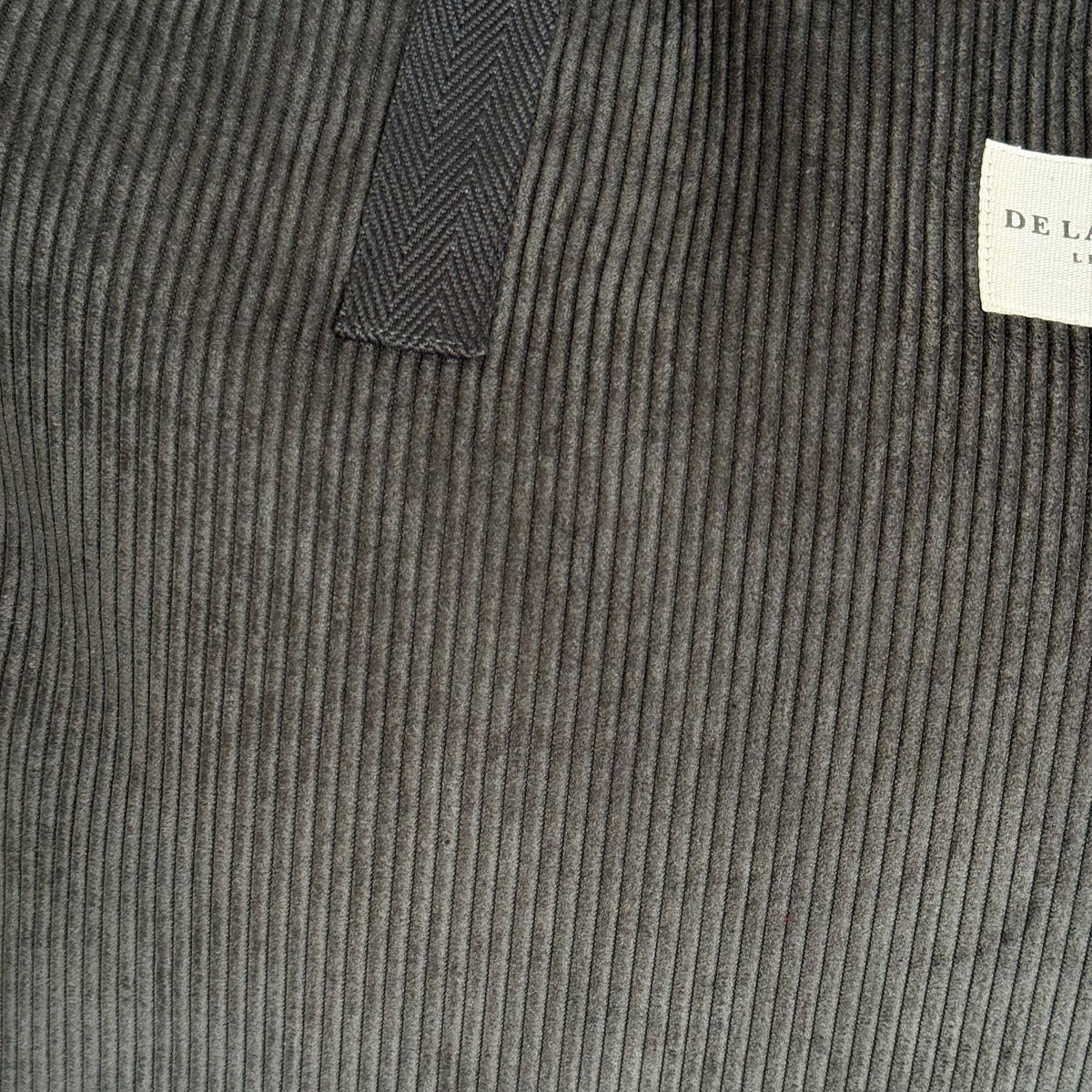 Close-up of the gray corduroy fabric and DE LA MUR Line label on the Boni weekender