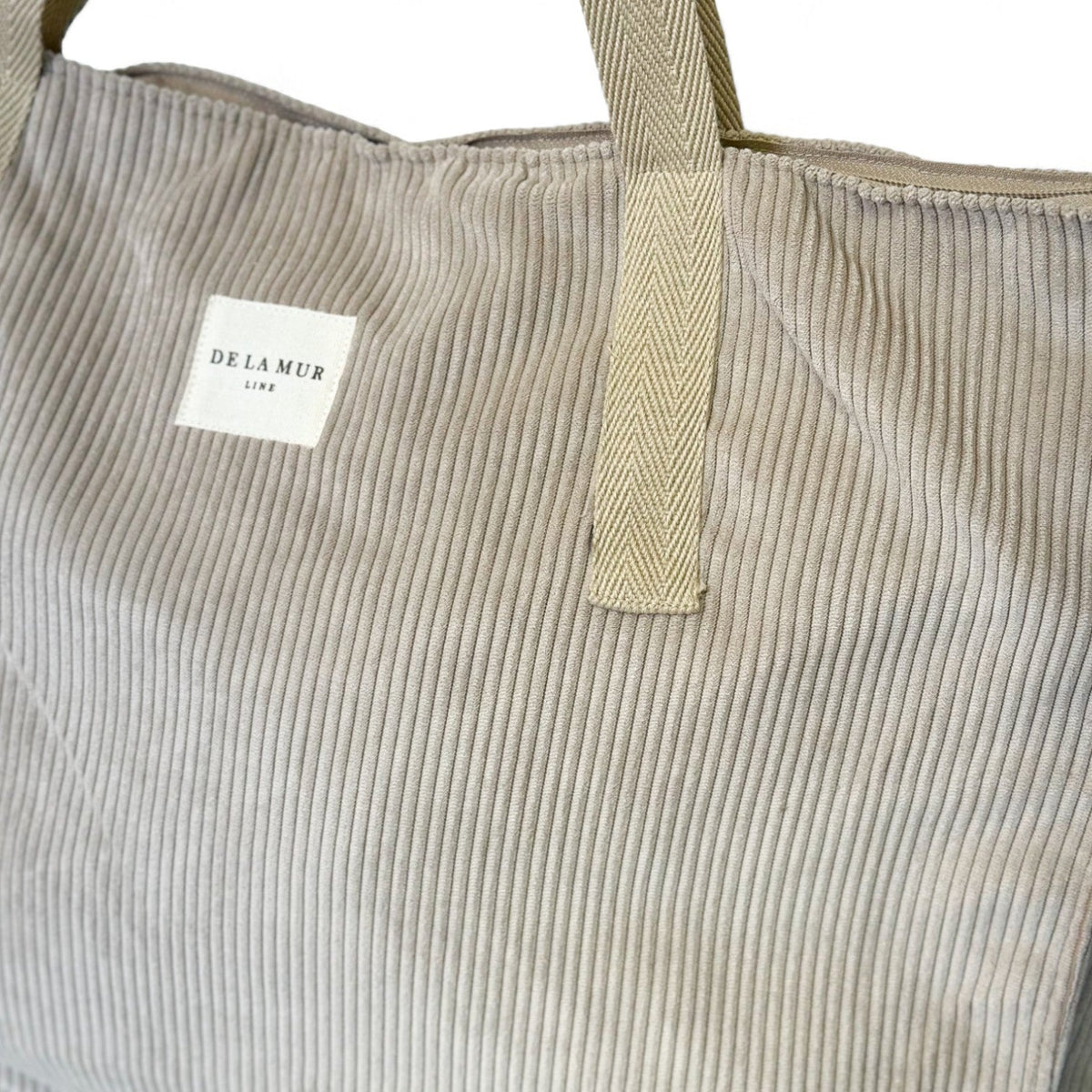 Detail of DE LA MUR weekender bag corduroy texture, handle and woven label