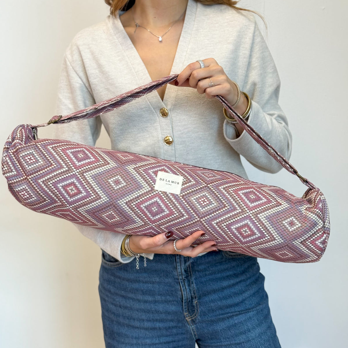 Model carrying the DE LA MUR Nana pink and lilac jacquard yoga mat bag