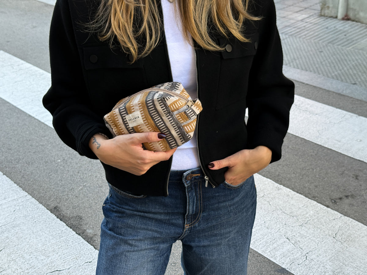 Model holding the DE LA MUR Tron striped jacquard pouch on a city crosswalk