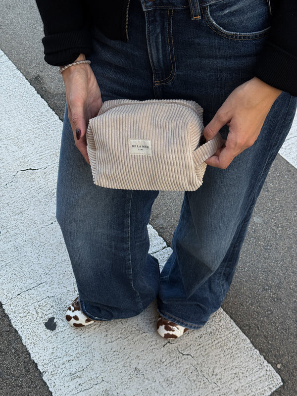 Model holding the DE LA MUR corduroy squared makeup bag outdoors, lifestyle shot