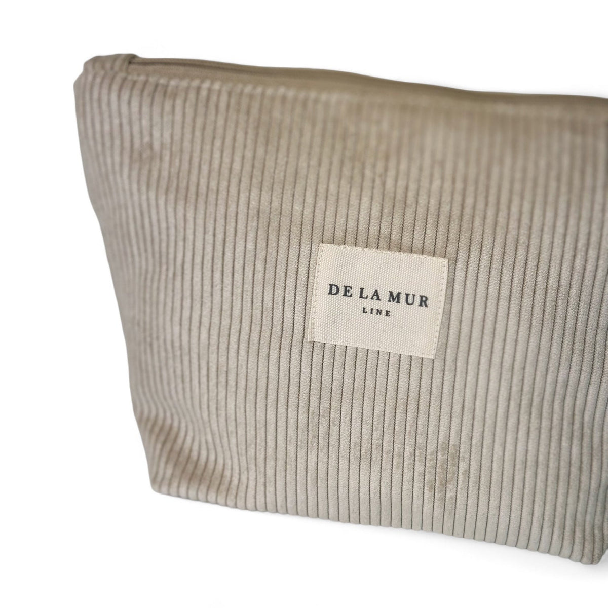 Close-up of the beige corduroy fabric and DE LA MUR Line label on the Tofe makeup bag