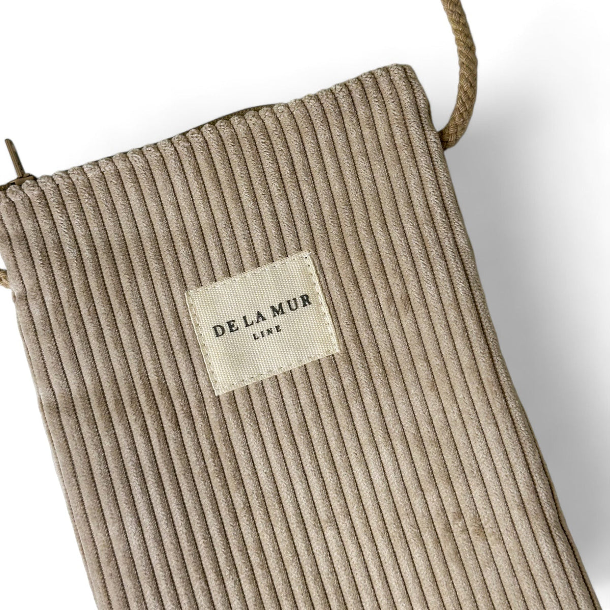 Close-up of DE LA MUR phone sleeve corduroy texture and woven Line label